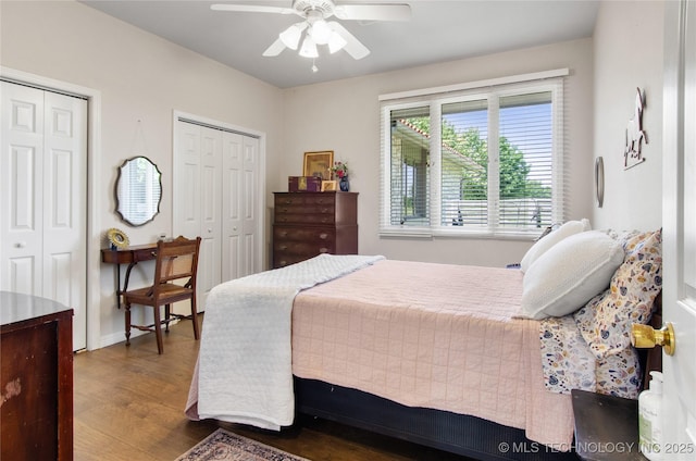 bedroom with ceiling fan, dark hardwood / wood-style floors, and two closets