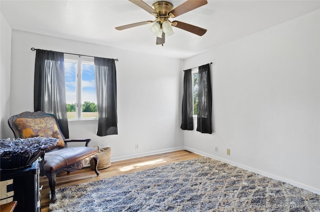 sitting room with ceiling fan and wood-type flooring