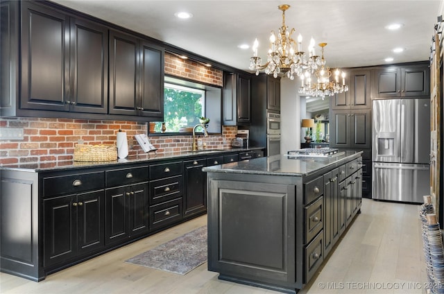 kitchen with a center island, stainless steel appliances, an inviting chandelier, pendant lighting, and light wood-type flooring