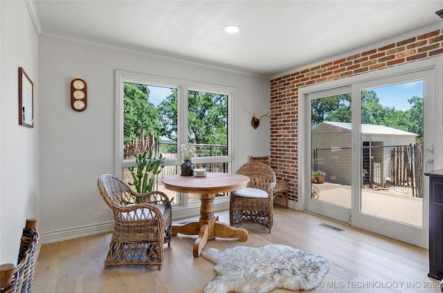 living area with light hardwood / wood-style floors, crown molding, and brick wall