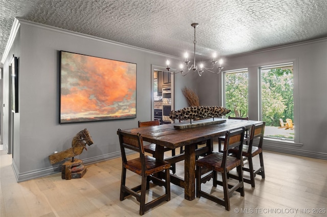 dining room with a textured ceiling, light wood-type flooring, an inviting chandelier, and crown molding