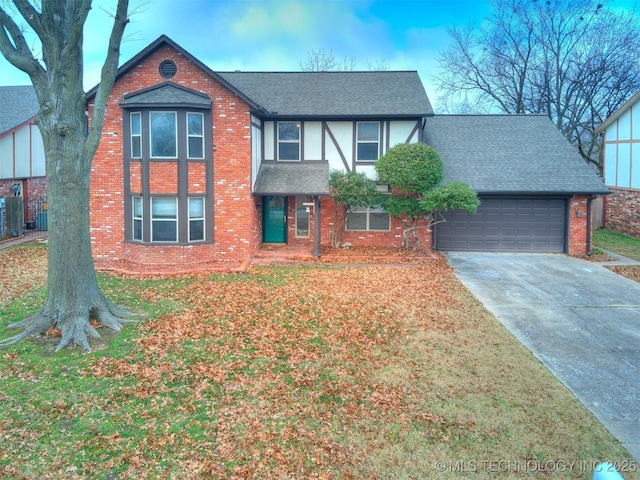 tudor house with central air condition unit, a front lawn, and a garage