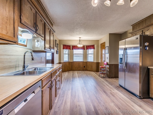 kitchen featuring appliances with stainless steel finishes, a textured ceiling, sink, pendant lighting, and light hardwood / wood-style floors