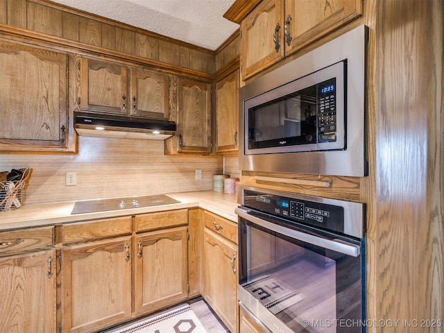 kitchen with a textured ceiling, stainless steel appliances, and backsplash