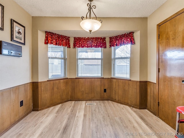 unfurnished dining area featuring light hardwood / wood-style floors and a textured ceiling