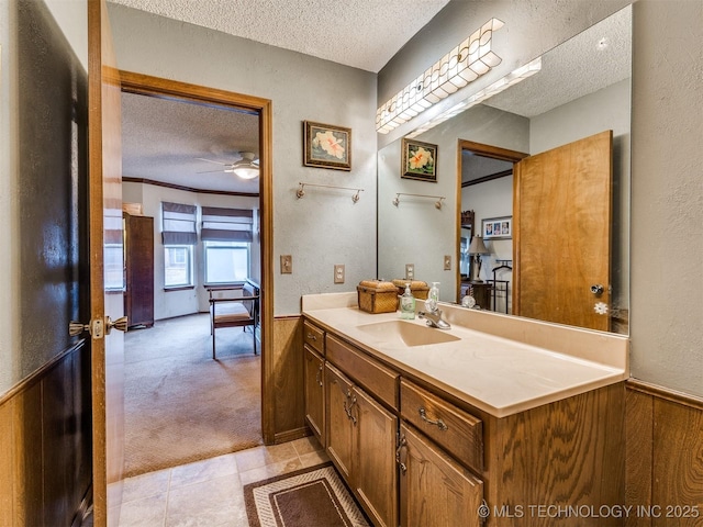 bathroom with vanity, ceiling fan, a textured ceiling, and wooden walls