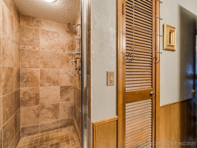 bathroom with a textured ceiling, a shower with door, and wood walls