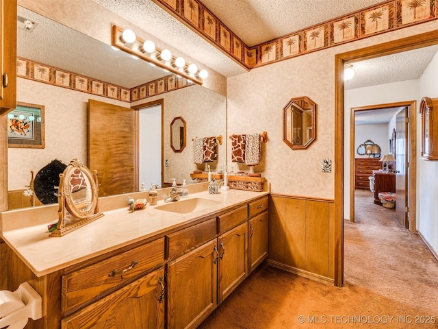 bathroom with vanity, wood walls, and a textured ceiling