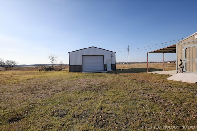 view of yard featuring a rural view, a garage, and an outdoor structure