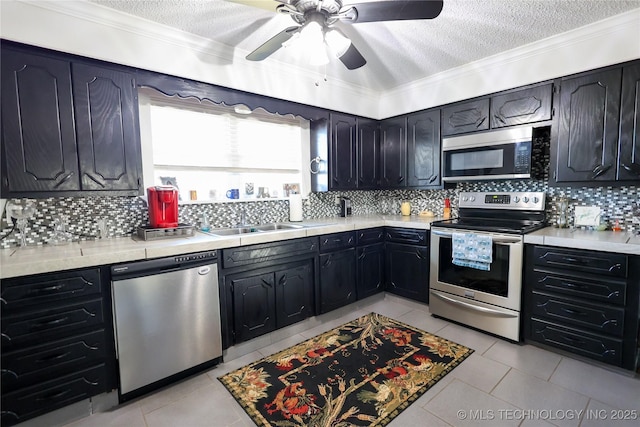 kitchen featuring appliances with stainless steel finishes, a textured ceiling, tasteful backsplash, and light tile patterned floors