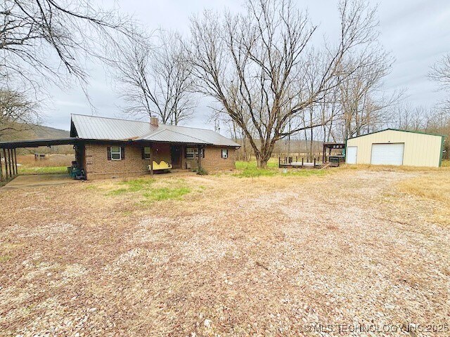 view of yard featuring a carport, a garage, and an outdoor structure