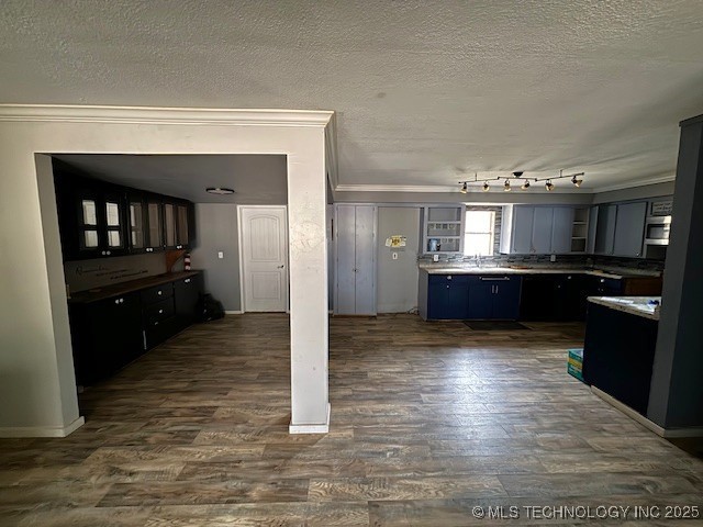 kitchen with a textured ceiling, dark hardwood / wood-style floors, and ornamental molding