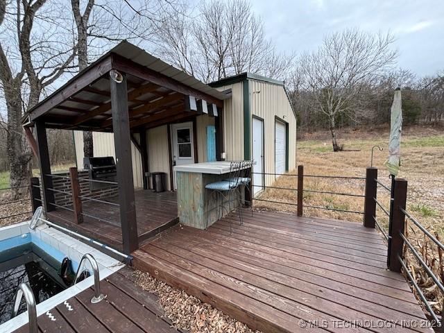 wooden terrace featuring a grill and an outdoor structure