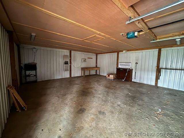 garage featuring electric panel, wooden walls, and a garage door opener