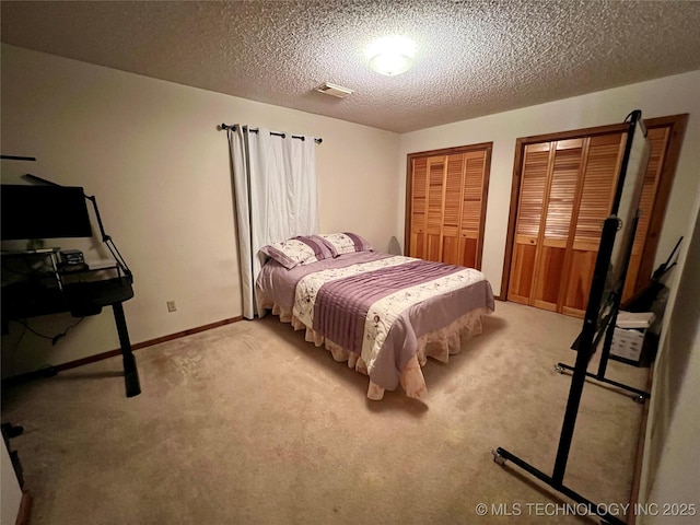 carpeted bedroom with a textured ceiling and two closets