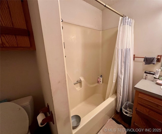 full bathroom featuring shower / bath combo with shower curtain, vanity, a textured ceiling, and toilet