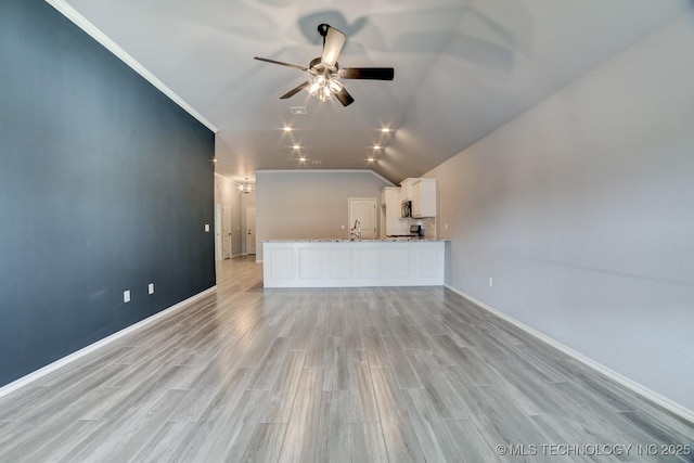 unfurnished living room featuring sink, crown molding, vaulted ceiling, ceiling fan, and light hardwood / wood-style floors