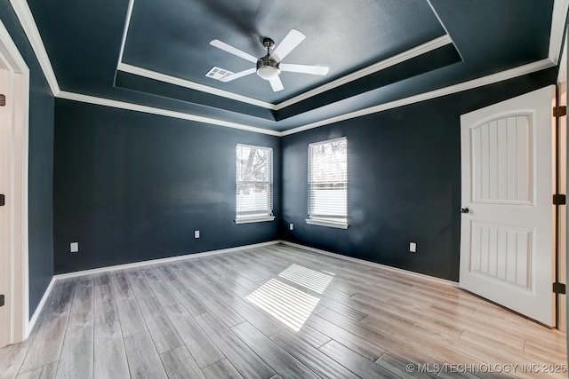 empty room with a raised ceiling, ceiling fan, and crown molding