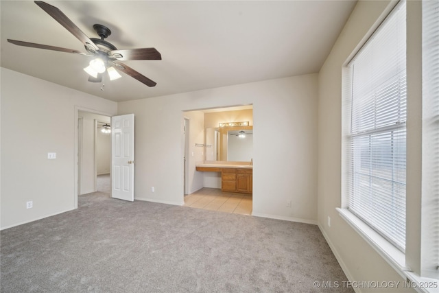 unfurnished bedroom with ceiling fan, multiple windows, light carpet, and ensuite bath