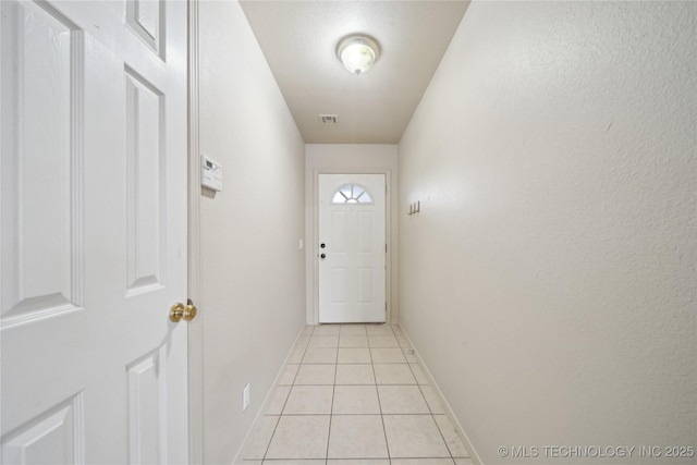 doorway with light tile patterned floors and a textured ceiling