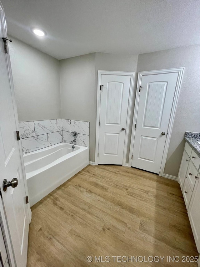 bathroom with a tub, hardwood / wood-style floors, and vanity