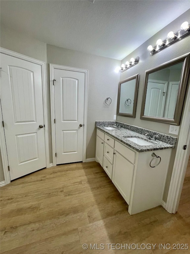 bathroom featuring vanity, wood-type flooring, and a textured ceiling