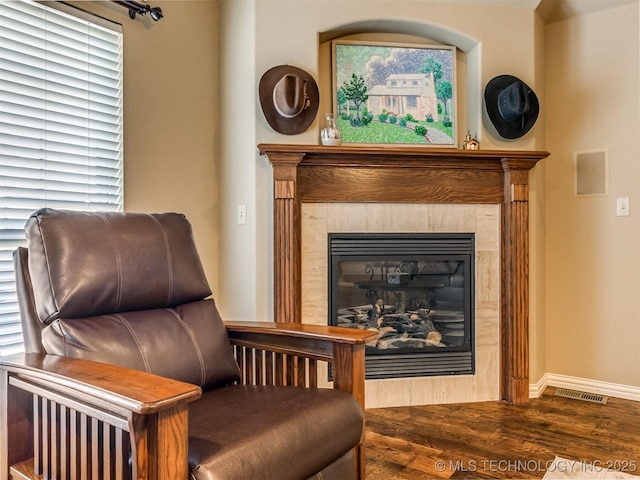 living area with dark hardwood / wood-style floors and a tiled fireplace