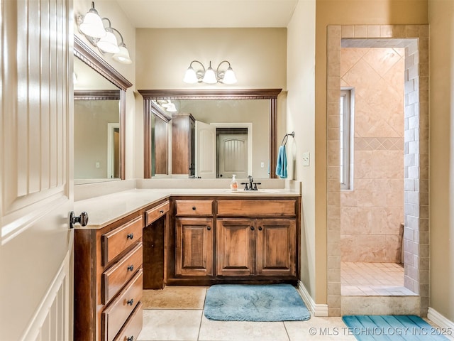 bathroom with tiled shower, vanity, and tile patterned flooring