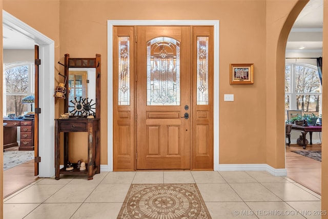 entrance foyer featuring light tile patterned floors and ornamental molding