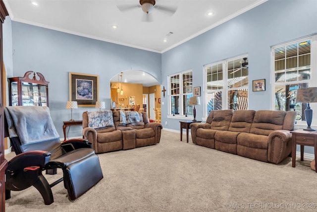 carpeted living room featuring ceiling fan, ornamental molding, and a high ceiling