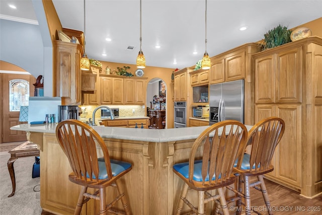 kitchen with tasteful backsplash, a breakfast bar, crown molding, pendant lighting, and built in fridge