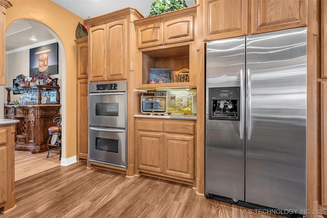 kitchen featuring crown molding, stainless steel appliances, and light hardwood / wood-style flooring