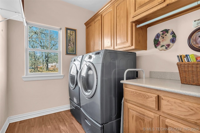 laundry room featuring cabinets, separate washer and dryer, and light hardwood / wood-style floors