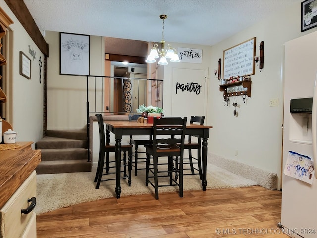 dining room featuring light hardwood / wood-style flooring, a chandelier, and a textured ceiling