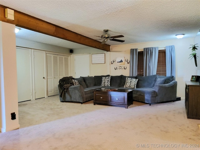 living room with ceiling fan, beam ceiling, light colored carpet, and a textured ceiling