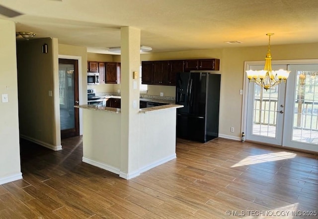 kitchen with french doors, black fridge, a notable chandelier, stove, and decorative light fixtures