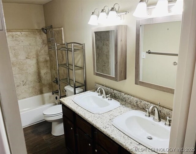 full bathroom with vanity, wood-type flooring, tiled shower / bath combo, and toilet