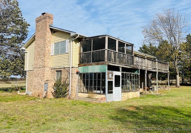 rear view of house with a sunroom, a yard, and a wooden deck