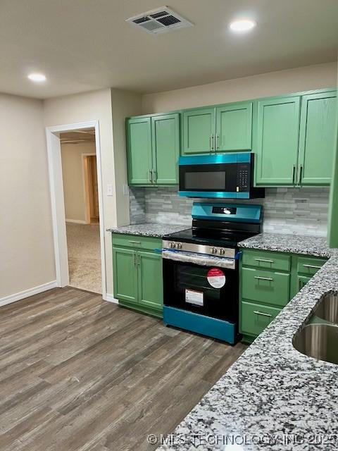 kitchen with backsplash, stainless steel stove, and green cabinets