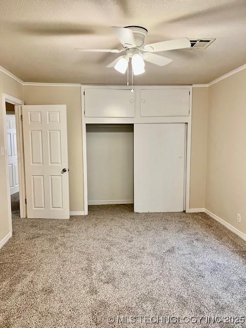 unfurnished bedroom featuring ceiling fan, crown molding, light carpet, and a closet