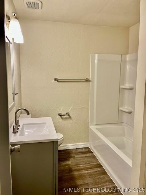 full bathroom with hardwood / wood-style floors, vanity, shower / bath combination, and toilet