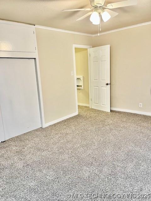 unfurnished bedroom featuring carpet flooring, a closet, ceiling fan, and crown molding