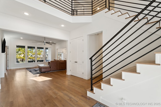 staircase with hardwood / wood-style flooring, ceiling fan, and a high ceiling