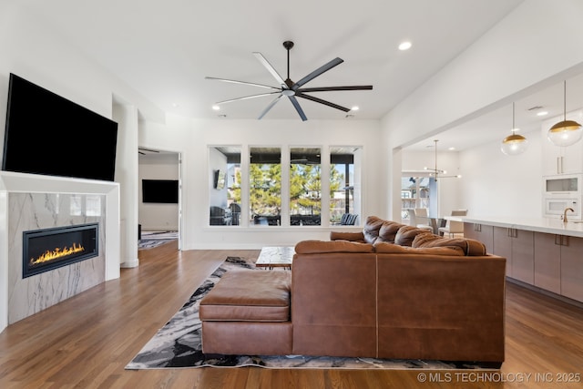 living room featuring a high end fireplace, a notable chandelier, and light wood-type flooring