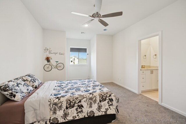 bedroom featuring ensuite bathroom, light colored carpet, and ceiling fan