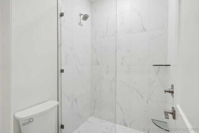 bathroom featuring toilet and a tile shower