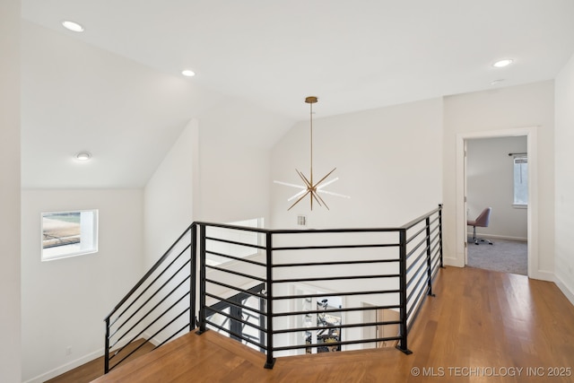 staircase featuring lofted ceiling, wood-type flooring, and a chandelier