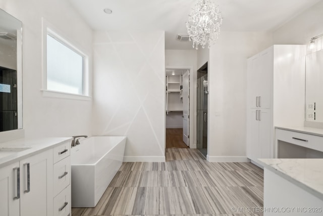 bathroom with vanity, a notable chandelier, and a tub to relax in