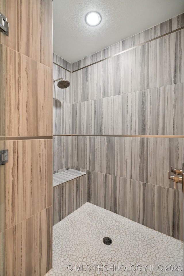 bathroom with a tile shower and a textured ceiling