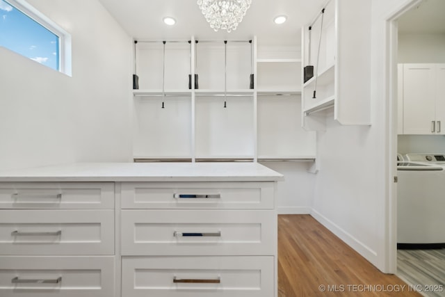 walk in closet featuring an inviting chandelier, washer / dryer, and light hardwood / wood-style flooring